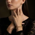 A woman wearing the Elora Vine 18k gold diamond bracelet in an Art Nouveau style, paired with a black lace dress.