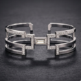 Architectural silver Icon Cuff featuring a central baguette diamond, triple-band open frame, and geometric pavé-set diamond accents.