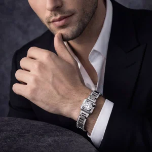 A close-up view of a man's wrist featuring a high-end square diamond watch paired with a tailored black suit jacket.