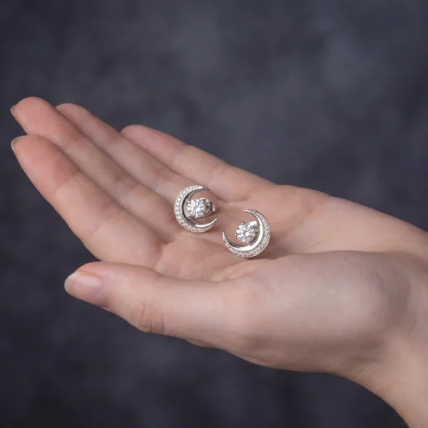 Hand holding crescent moon stud earrings