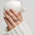 Woman's hand wearing opal floral ring with white sweater