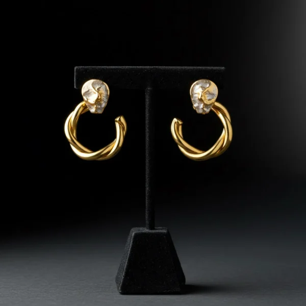 gilded-elegance-hoop-earrings-display Twisted gold hoop earrings with textured silver studs on a black stand.