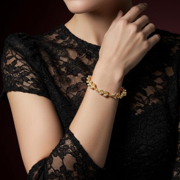 Delicate gold leaf bracelet with diamonds on woman in lace dress.