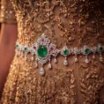 Close-up of intricate gold embroidery and emerald waist chain.