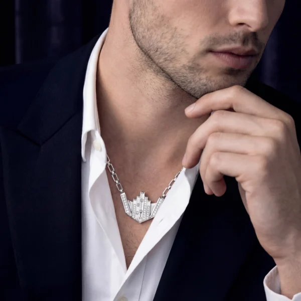 Man in white shirt and suit jacket with skyline necklace.