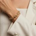 Woman wearing Naturaleza gold vine bracelet with white blazer.