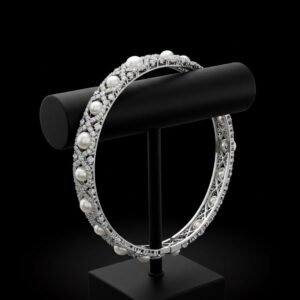 18k white gold bracelet with round white pearls and diamonds on a black display stand.