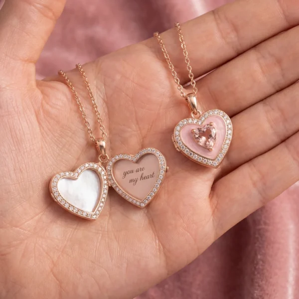 Close-up of a woman wearing an open rose gold heart locket with an engraving.