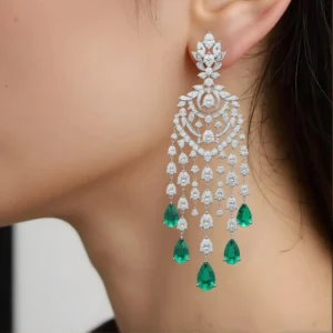 Macro shot of silver chandelier earrings featuring green emerald teardrops.