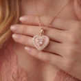 Close-up of a woman wearing a closed pink heart locket with rose gold accents.